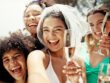 Brud og vennegjeng smiler og skåler med champagne under utdrikningslag i solen, klare for en fest full av latter og minner.